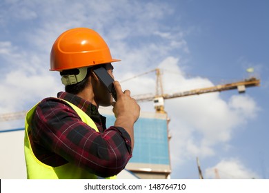 Construction worker activity with mobile phone under new building