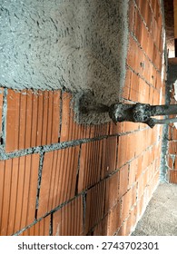 Construction worker applying cement plaster coating to a wall using a machine. Machine Plastering, process involves a plastering machine that sprays mortar onto surfaces to achieve a smooth and consistent finish. 