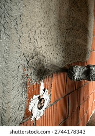 Construction worker applying cement plaster coating to a wall using a machine. Machine Plastering, process involves a plastering machine that sprays mortar onto surfaces to achieve a smooth and consistent finish. 
