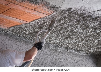 Construction Worker Applying Cement Plaster Coating On The Ceiling With Plastering Machine