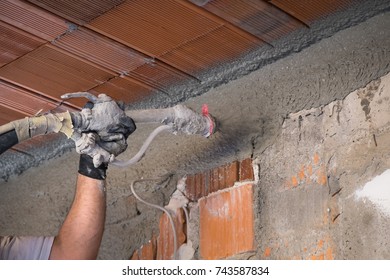 Construction Worker Applying Cement Plaster On The Wall Surface With Plastering Machine