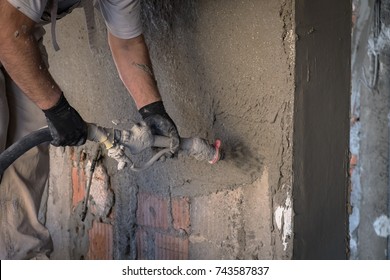 Construction Worker Applying Cement Plaster On The Wall Surface With Plastering Machine