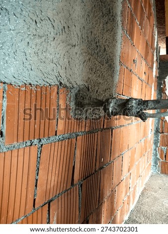Construction worker applying cement plaster coating to a wall using a machine. Machine Plastering, process involves a plastering machine that sprays mortar onto surfaces to achieve a smooth and consistent finish. 