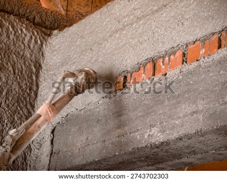 Construction worker applying cement plaster coating to a wall using a machine. Machine Plastering, process involves a plastering machine that sprays mortar onto surfaces to achieve a smooth and consistent finish. 