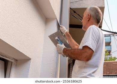 Construction worker applying final decorative facade plaster paste. Home renovation. Builders apartment improvement or restoration works.