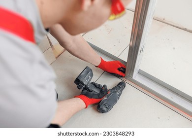 Construction worker assemble wall with attach to metal frame with screwdriver for drywall bathroom.