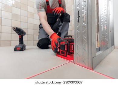 Construction worker assemble wall with attach to metal frame with laser level and screwdriver for drywall in bathroom.