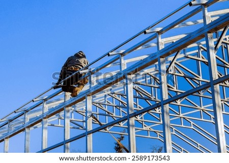 Construction worker is assembling framework metal structure of building commercial storage