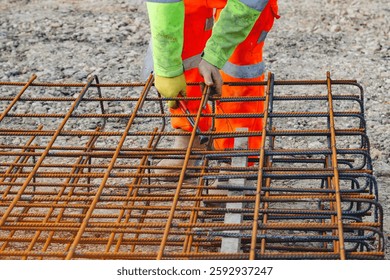 Construction worker assembling rebar framework at a building site during daylight