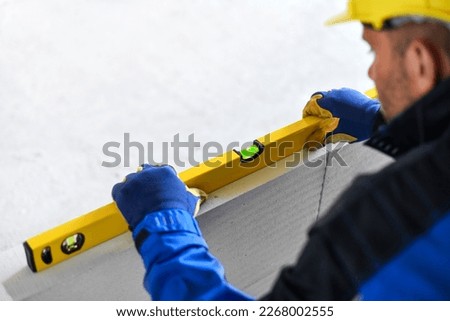 Construction Worker in blue uniform with spirit level, Workers work with bubble gauge transducer, water level detail with worker hands.