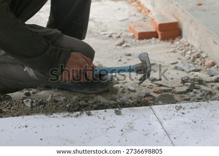Construction Worker Breaking Concrete Floor with Hammer During Home Renovation