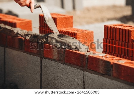 Construction worker bricklayer lays bricks for new structure at building site using tools and materials for masonry work