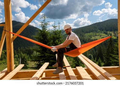 Construction Worker Builds A House. Caucasian Contractor And The Wooden House Frame.Energy Efficient Frame House. New Framing Construction Of A House. Construction Crew Working,  Commercial Apartment