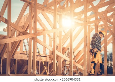 A construction worker is carefully assembling a wooden frame under the bright afternoon sun. Ladders and tools are scattered around the active site.
