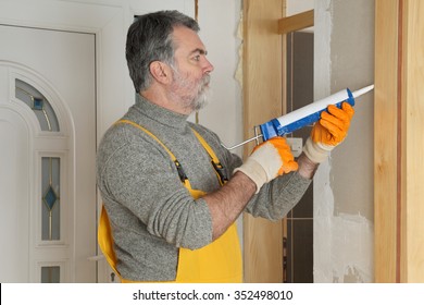 Construction Worker Caulking Door  With Silicone Glue Using Cartridge