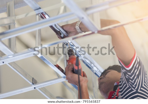 Construction Worker Ceiling Metal Frame Screwdriver Stock