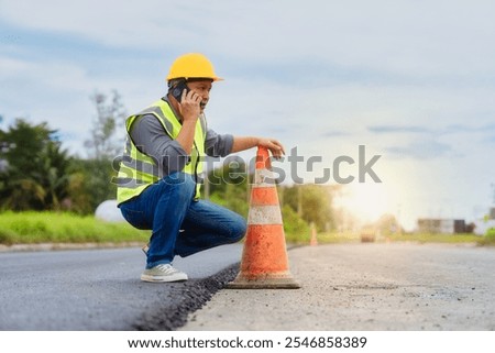 Construction worker checking roadwork progress with phone call