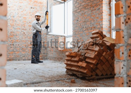 Construction worker checking window alignment with a spirit level during house renovation, working on interior brick wall