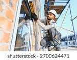 Construction worker checking window frame alignment with a spirit level on a building site. New house construction