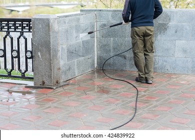 Construction Worker Cleaning Street With Water Hose