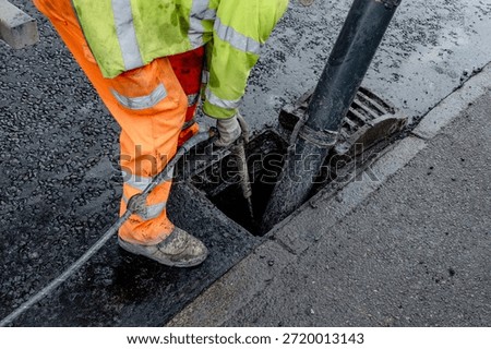 Construction worker clears drainage system on urban street using jet wash and vac-ex