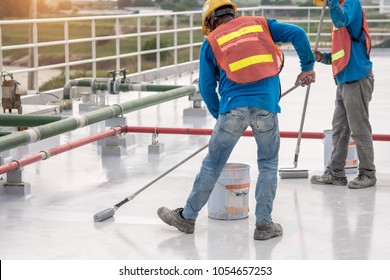 Construction worker coating epoxy paint at roof slab for water proof protection