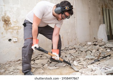 Construction worker collecting construction debris with a shovel. House renovation.