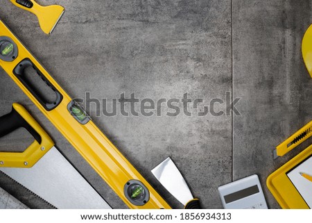 Construction worker concept. Yellow and black contractor equipment on gray tiles.