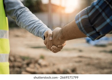 construction worker and contractor. Client shaking hands with team builder in the factory construction site.