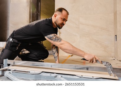 Construction worker cutting ceramic tile using tile cutter while working on bathroom renovation