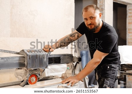 Construction worker cutting ceramic tiles using a tile saw during renovation works in bathroom