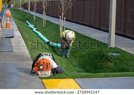 Construction worker in deep trench protected by Trench Box, coffin, while installing new 8 inch sewer line pipe under the road, building out infrastructure for new housing development
