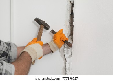 Construction Worker Demolishing Hole At Brick Wall With Chisel Tool And Hammer