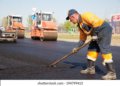 Construction Worker during Asphalting Road Works on Vibratory Rollers Machines background