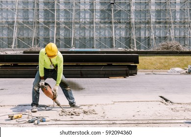 Construction Worker  Electric Drill Drilling Concrete Ground In Construction Area