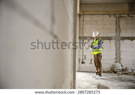 Construction worker engineer evaluating blueprints in a building site with safety gear and protective clothing