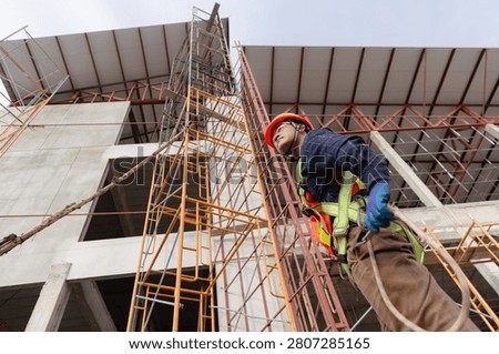Construction worker engineering at a building site using safety gear while operating scaffolding and equipment for structural work