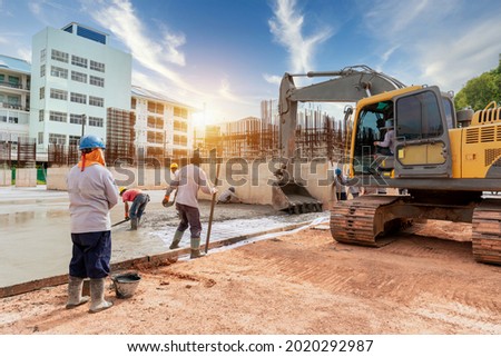 A construction worker with excavator heavy machine and cement truck for control a pouring concrete pump at building construction site 商業照片 © 