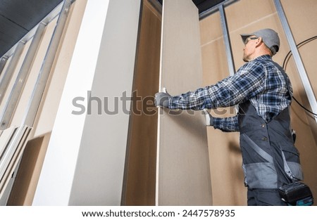 Construction Worker Fitting Piece of a Drywall Inside Newly Built Commercial Building