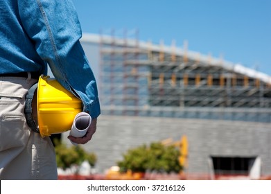 A Construction Worker Or Foreman At A Construction Site With Blue Prints And A Hard Hat