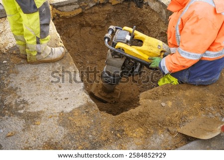 construction worker with a hand held vibratory compactor