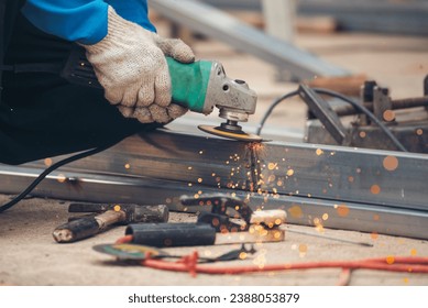 Construction Worker hands using Welding machinery iron metal sparking. Men hands wear protective glove Hot flame metal work cutting fire iron workshop. Locksmith use Welding machine cut metal process