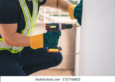 construction worker or handyman working with a drill machine at construction site
