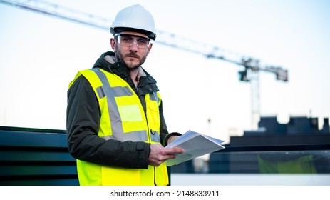 A construction worker in a hard hat helmet protect glasses looks forward at camera and smiles because of sustainability of industry. Concept of construction engineering works and real estate.  - Shutterstock ID 2148833911