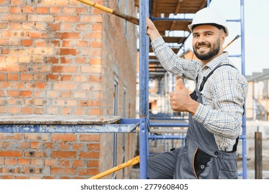 Construction worker in hard hat and overalls standing on scaffolding, giving a thumbs up gesture, indicating success and good work