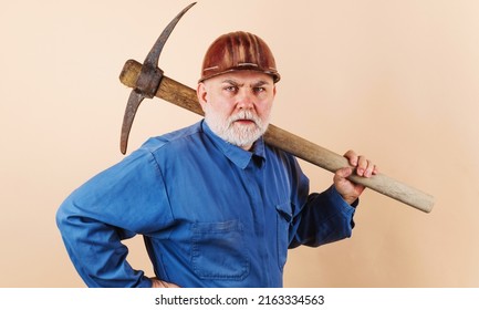 Construction worker in hard hat and uniform with pickaxe. Male laborer with building tools.
