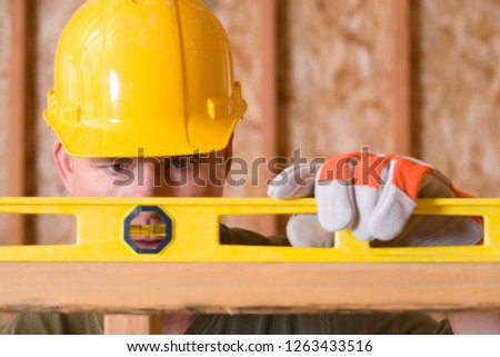 Construction worker in hard hat using spirit level on building site