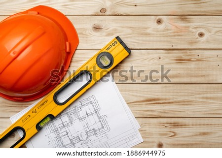 Construction worker hardhat, blueprints and .construction level, top view