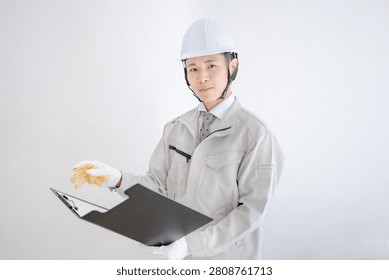 Construction worker in hardhat presenting open clipboard