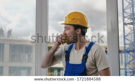 Construction worker having a break and eating apple.